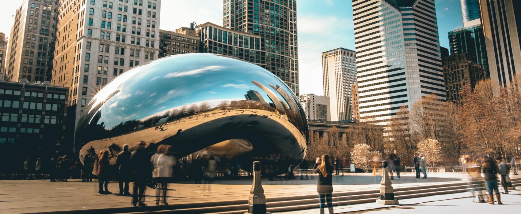 Chicago bean in front of the Chicago skyline as seen from Millennium Park